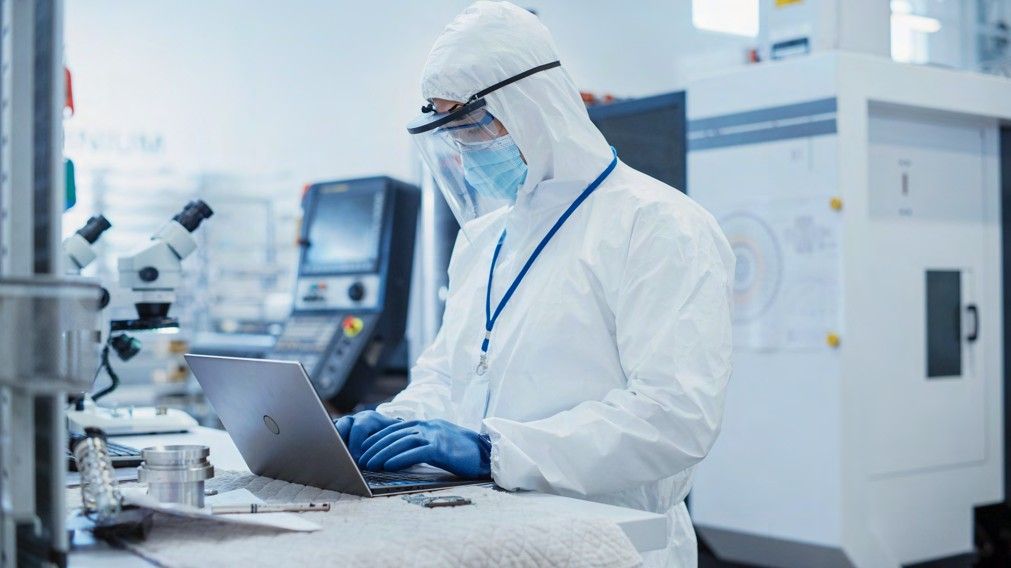 Engineer reviewing device data on a laptop in a manufacturing lab